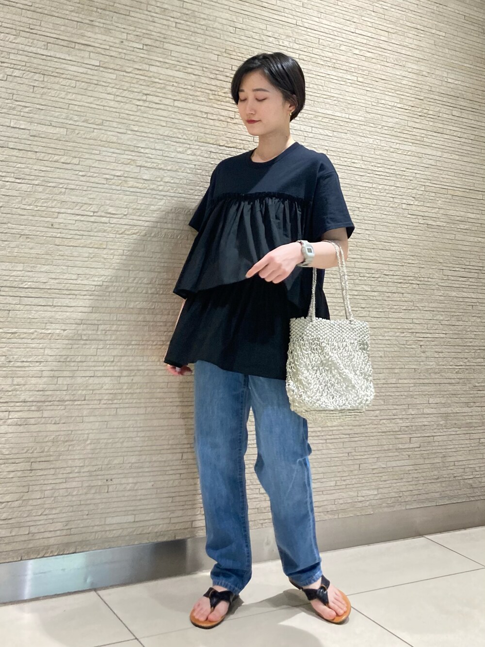 ブルー系のデニムパンツ、ブラック系のサンダルを着用したレディースの春コーディネートの2枚目の写真