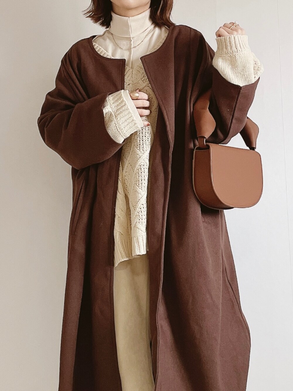 ブラウン系のジャケット/アウター、ベージュ系のニット/セーター、ホワイト系のスラックスを着用したレディースの冬コーディネートの3枚目の写真