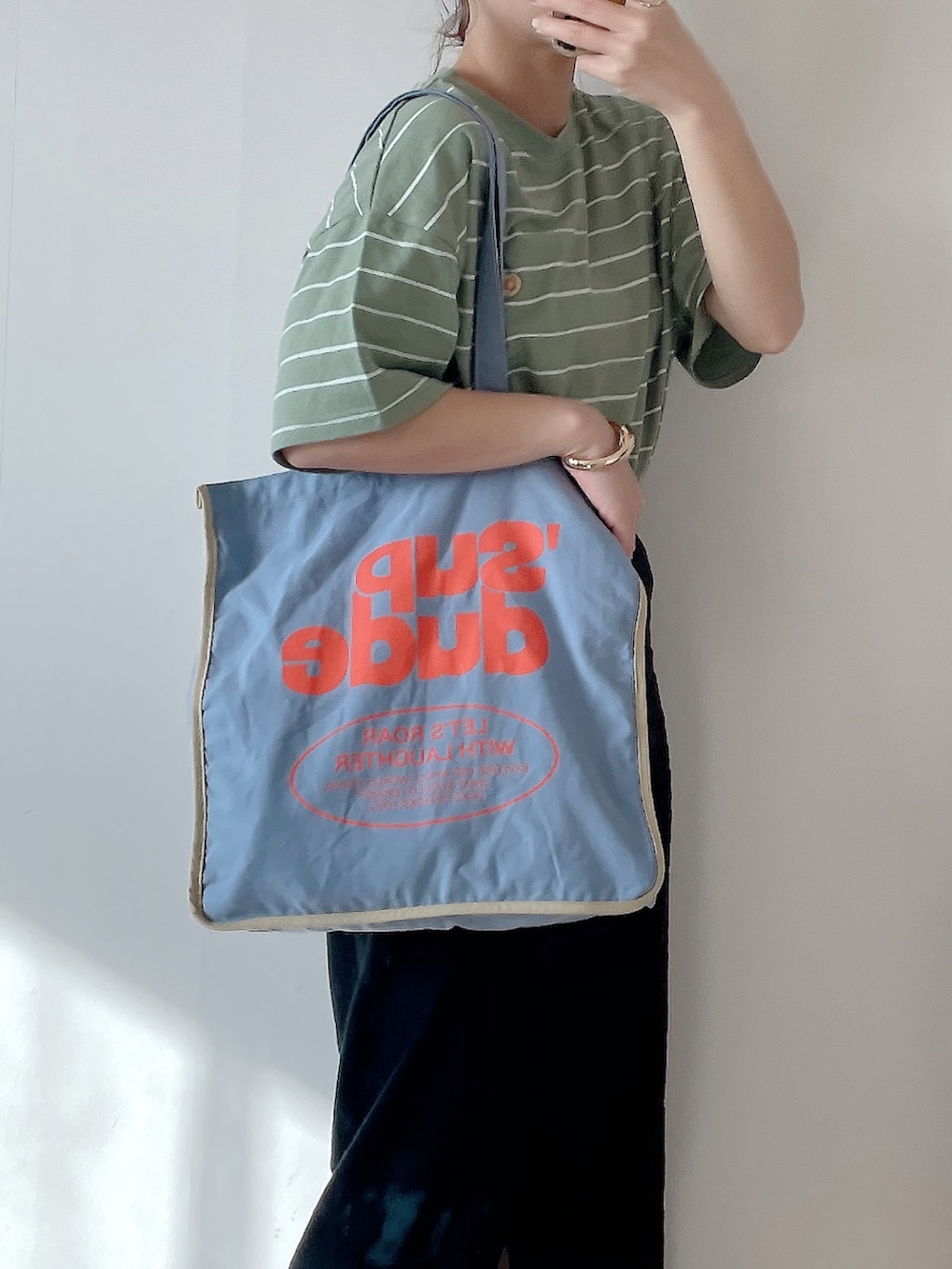 ブルー系のトートバッグ、グリーン系のTシャツ/カットソー、ホワイト系のスニーカーを着用したレディースの春コーディネートの3枚目の写真