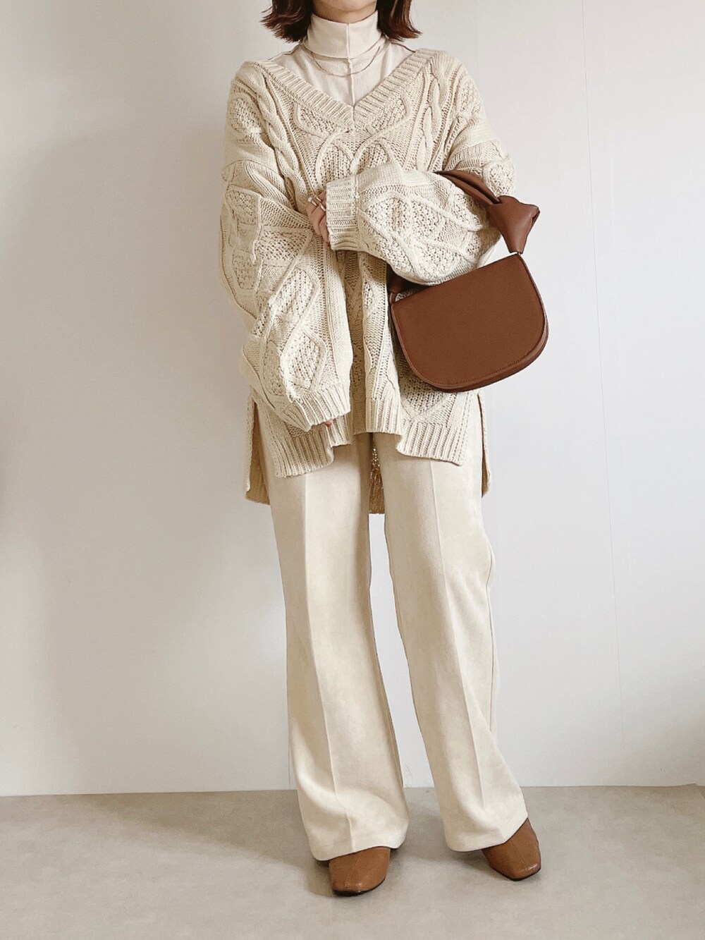 ブラウン系のジャケット/アウター、ベージュ系のニット/セーター、ホワイト系のスラックスを着用したレディースの冬コーディネートの4枚目の写真