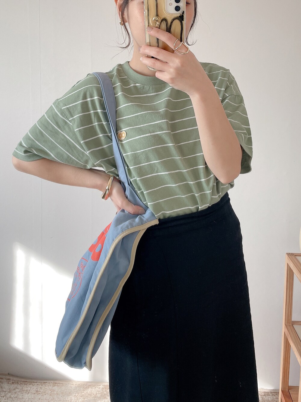 ブルー系のトートバッグ、グリーン系のTシャツ/カットソー、ホワイト系のスニーカーを着用したレディースの春コーディネートの2枚目の写真