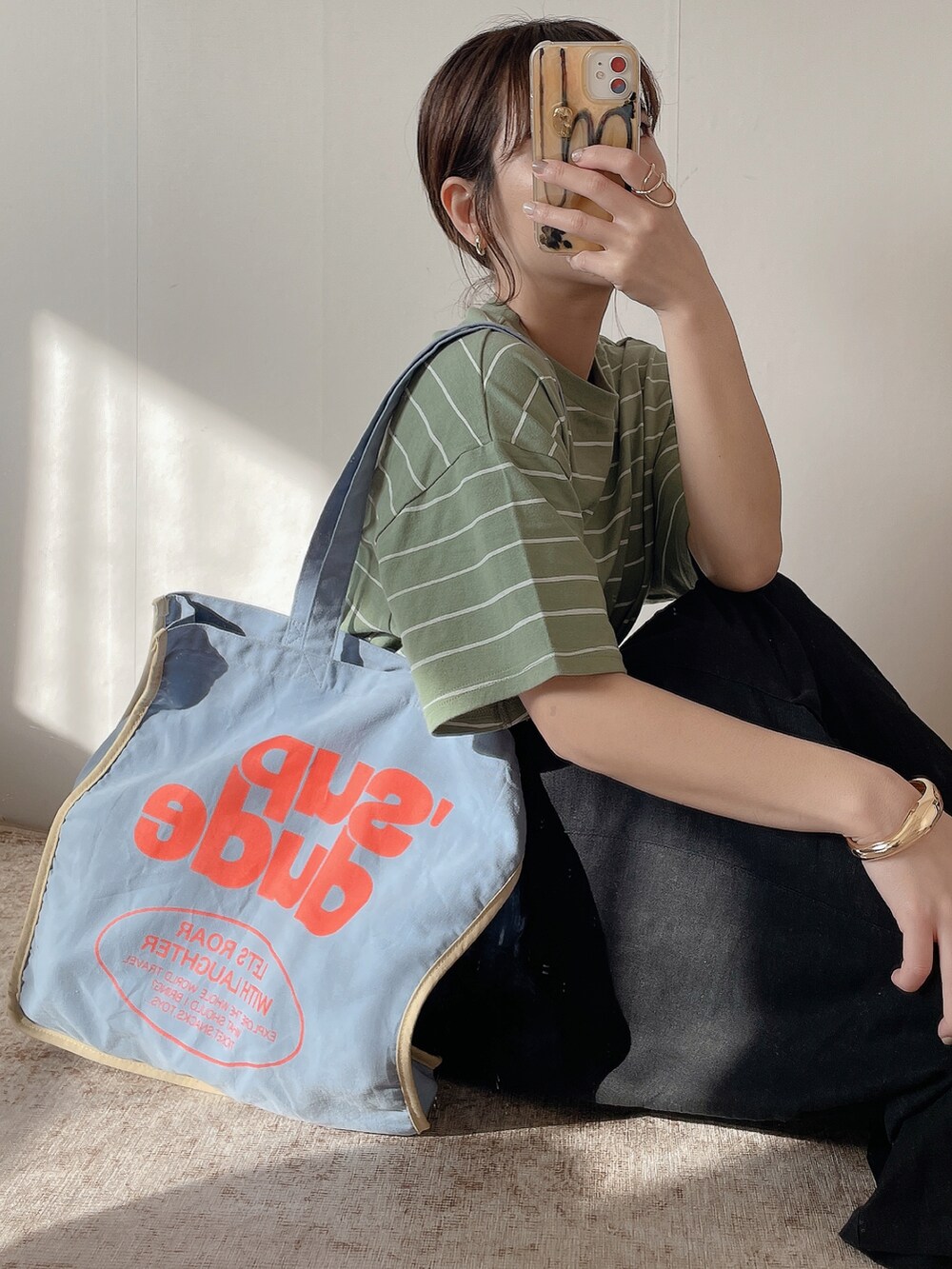 ブルー系のトートバッグ、グリーン系のTシャツ/カットソー、ホワイト系のスニーカーを着用したレディースの春コーディネートの4枚目の写真