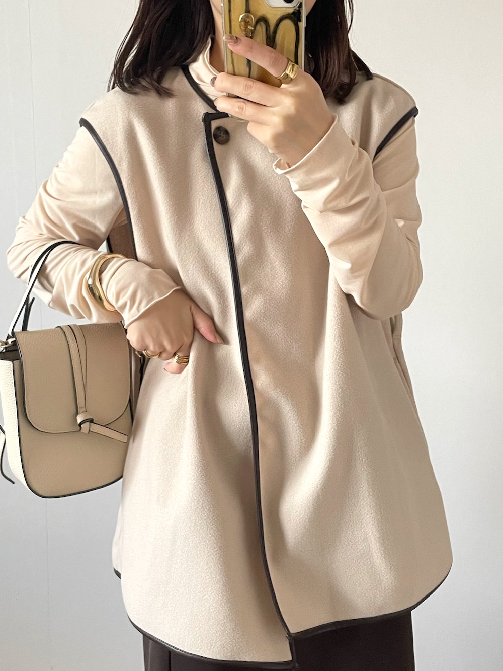 ホワイト系のベスト、ブラウン系のスカート、ホワイト系のショルダーバッグを着用したレディースの秋コーディネートの2枚目の写真