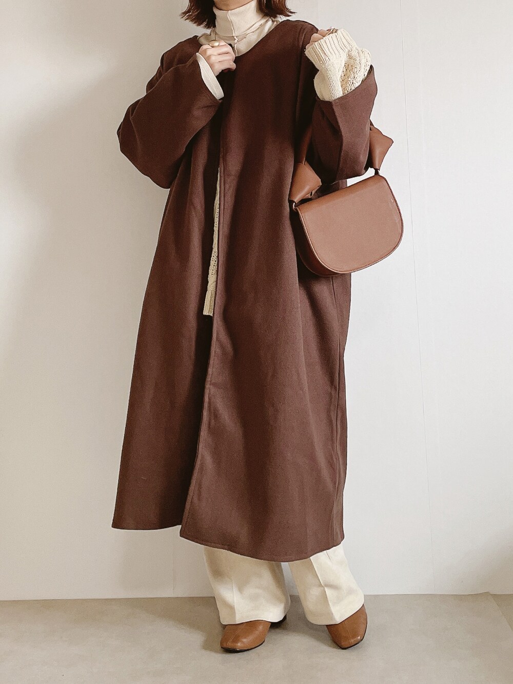 ブラウン系のジャケット/アウター、ベージュ系のニット/セーター、ホワイト系のスラックスを着用したレディースの冬コーディネートの2枚目の写真