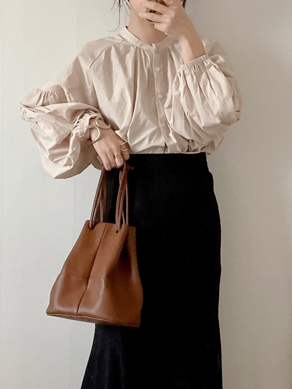 ブラック系のスカート、ブラウン系のショルダーバッグ、ベージュ系のサンダルを着用したレディースの春コーディネートの2枚目の写真