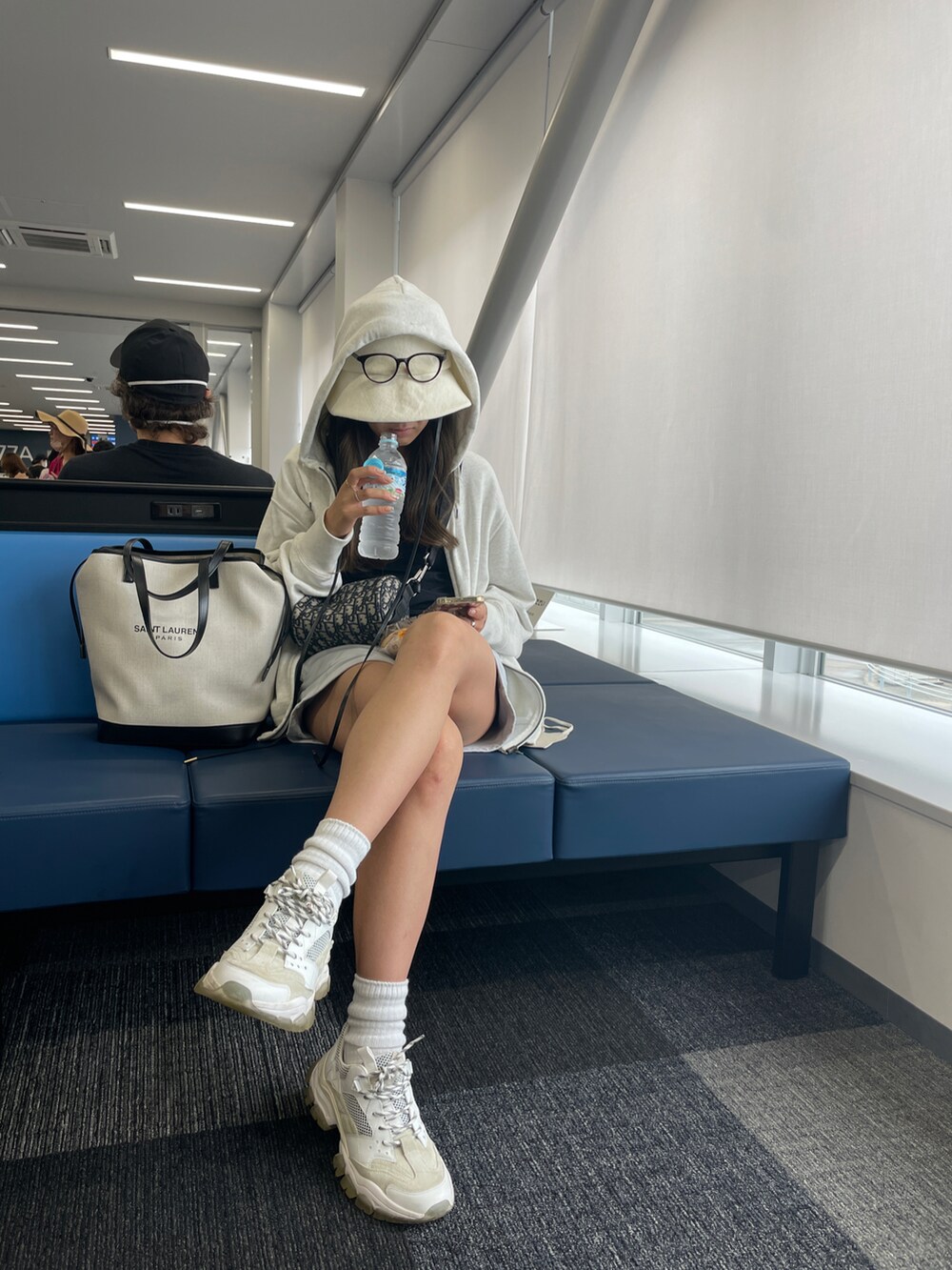 ブラック系のタンクトップ、ホワイト系のトートバッグ、ホワイト系のスニーカーを着用したレディースの夏コーディネートの2枚目の写真