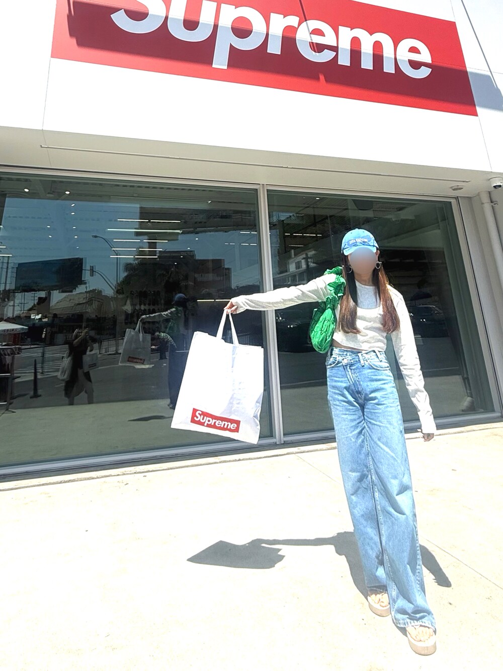 ブルー系のデニムパンツ、ベージュ系のTシャツ/カットソー、グリーン系のショルダーバッグを着用したレディースの秋コーディネートの2枚目の写真