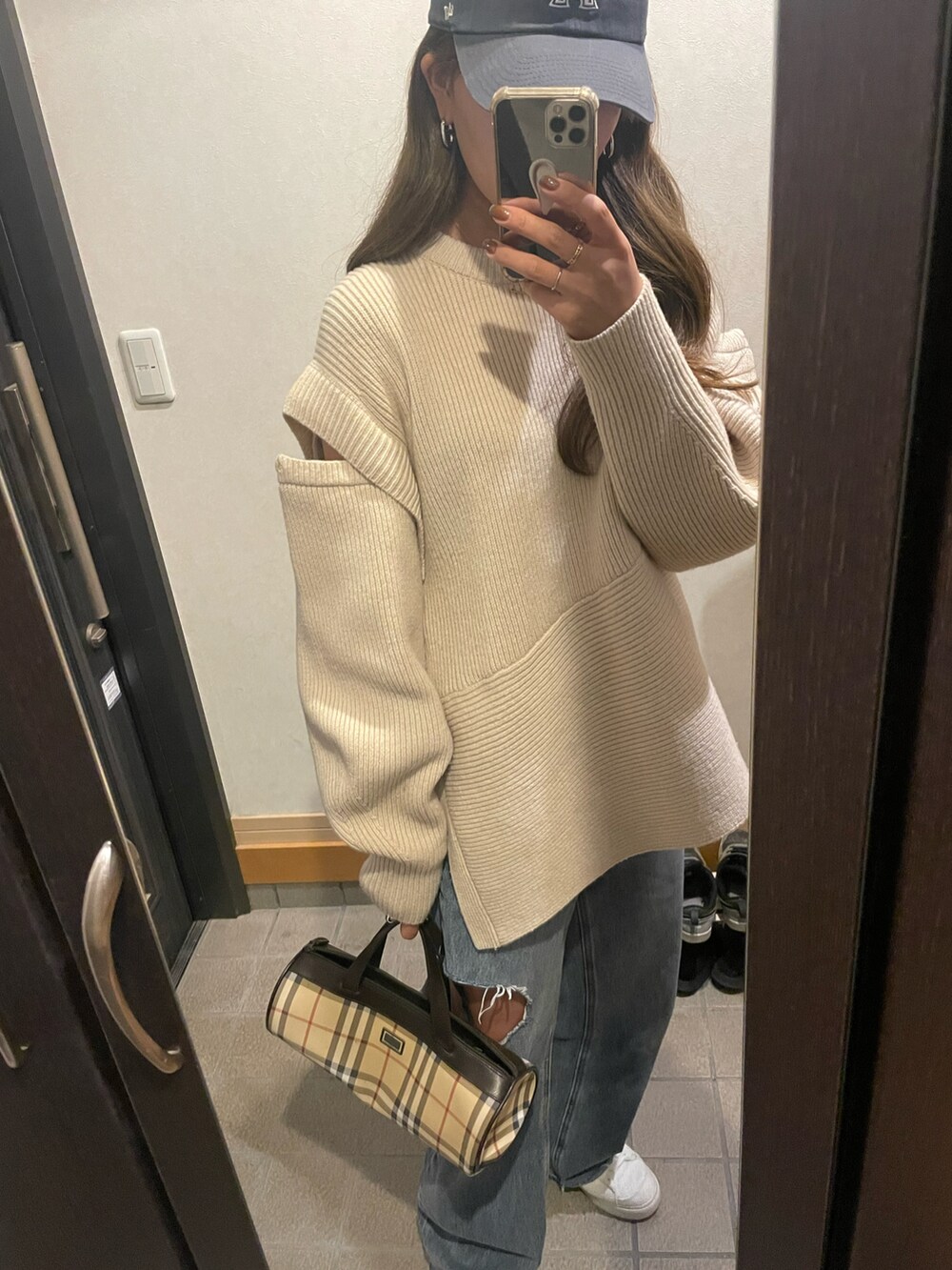 ホワイト系のニット/セーター、ベージュ系のドラムバッグ、ブルー系のデニムパンツを着用したレディースの秋コーディネートの2枚目の写真