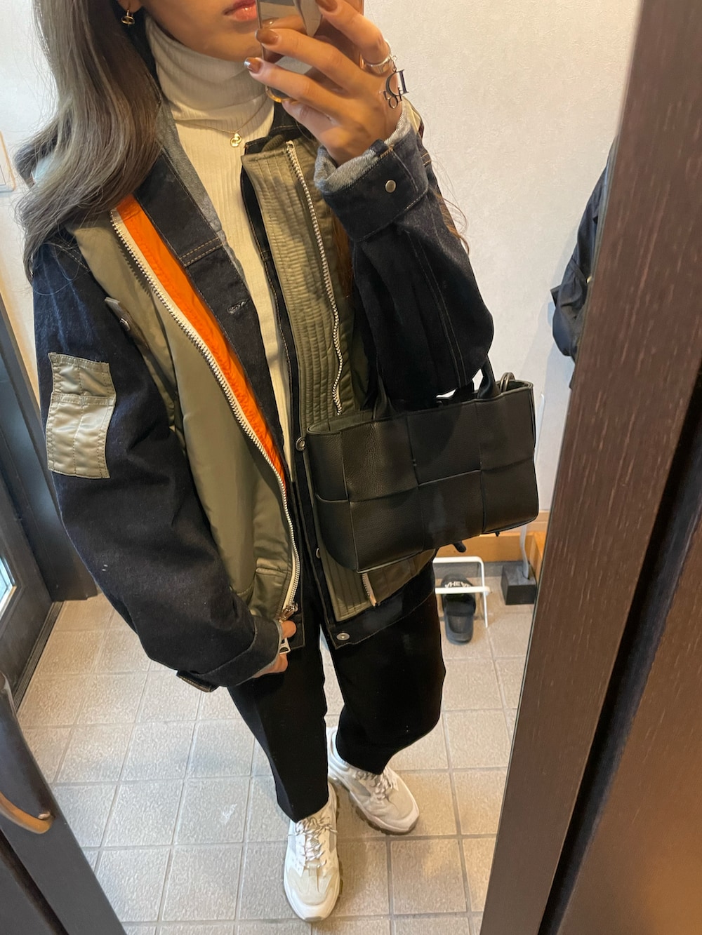 ホワイト系のスニーカー、ブラック系のスラックス、グリーン系のジャケット/アウターを着用したレディースの秋コーディネートの2枚目の写真