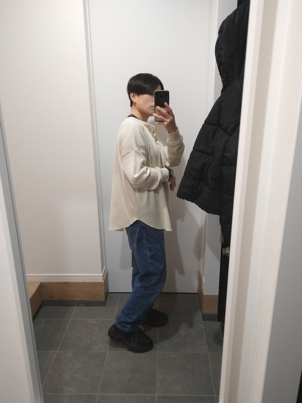 ベージュ系のTシャツ/カットソー、ブルー系のデニムパンツ、ブラック系のスニーカーを着用したレディースの冬コーディネートの2枚目の写真