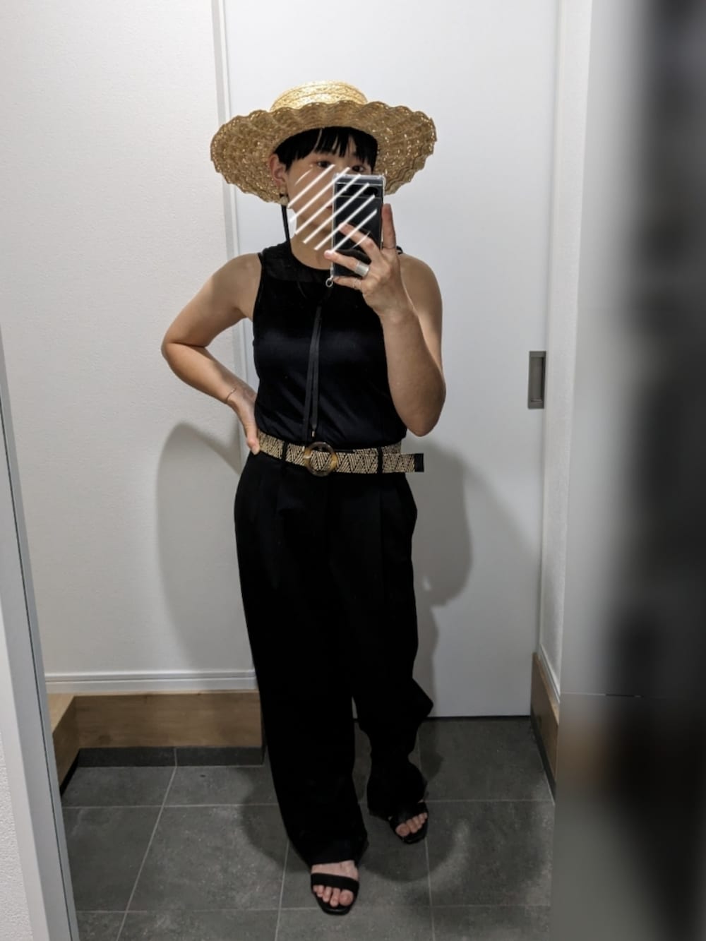 ブラック系のタンクトップ、ブラック系のスラックス、ブラック系のサンダルを着用したレディースの夏コーディネートの2枚目の写真