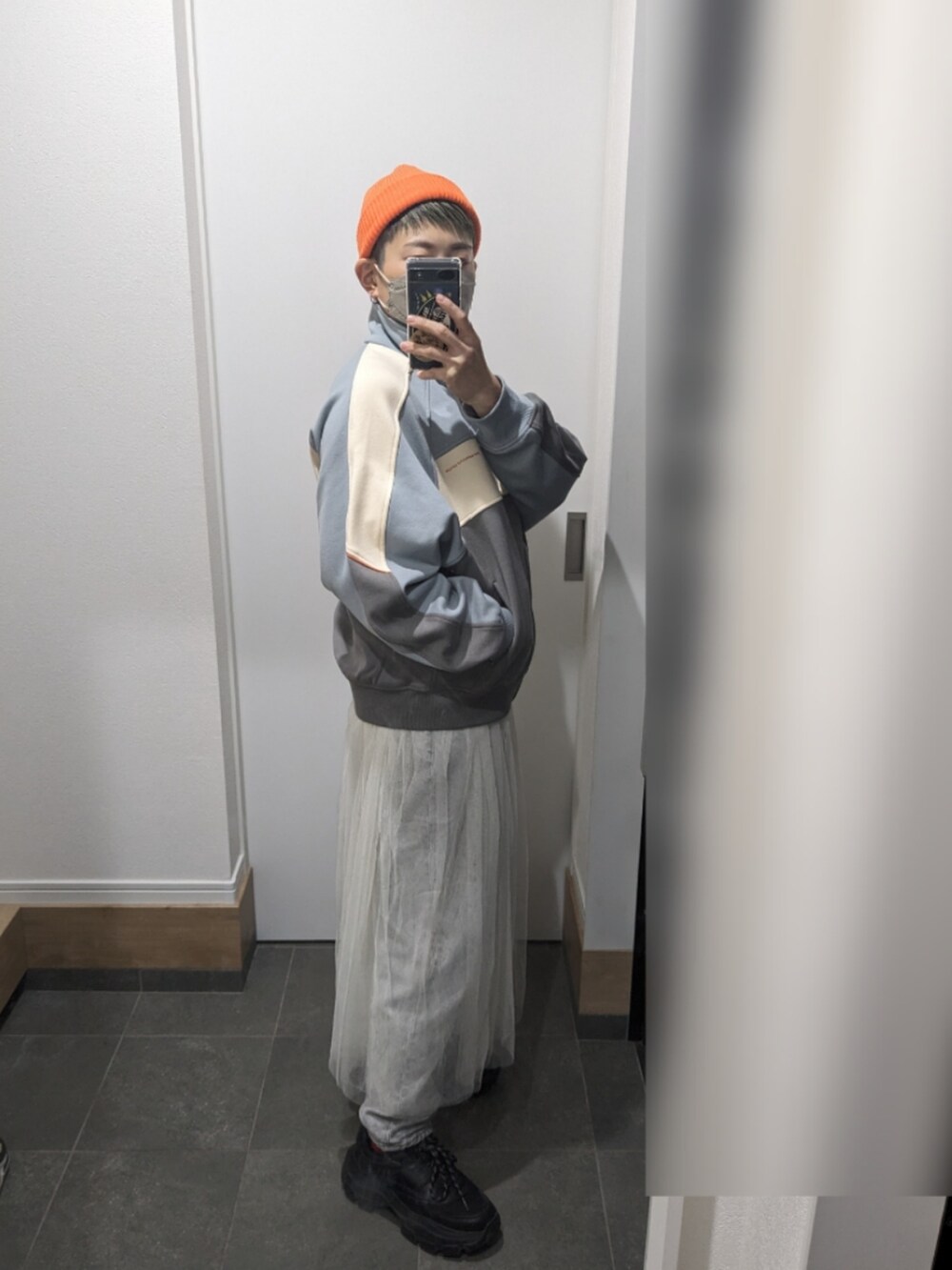 グレー系のジャージ、ホワイト系のスカート、ブラック系のスニーカーを着用したレディースの冬コーディネートの2枚目の写真