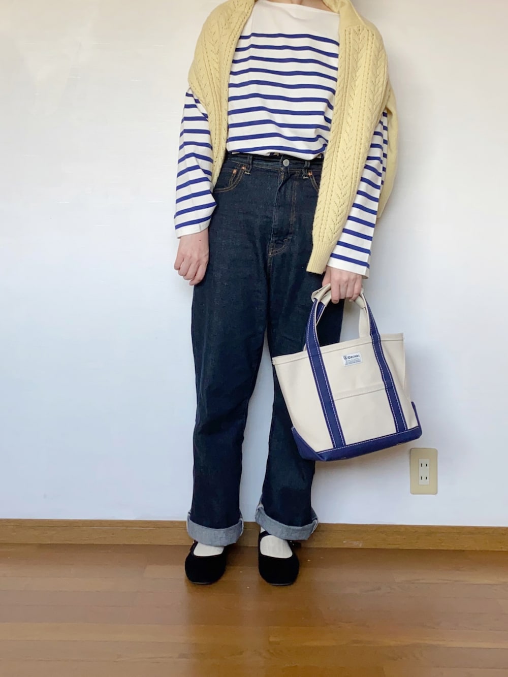 ブルー系のデニムパンツ、ブラック系のパンプス、ブルー系のトートバッグを着用したレディースの春コーディネートの2枚目の写真