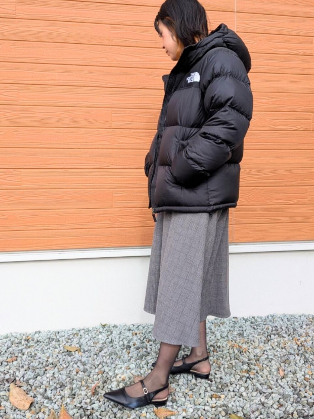 ブラック系のパンプス、グレー系のジャンパースカート、ブラック系のニット/セーターを着用したレディースの秋コーディネートの2枚目の写真
