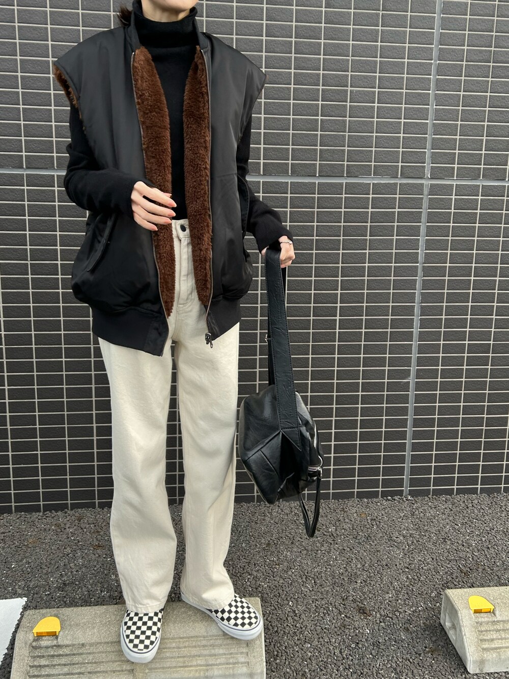 ブラック系のスニーカー、ホワイト系のデニムパンツ、ブラック系のボディバッグ/ウエストポーチを着用したレディースの冬コーディネートの2枚目の写真