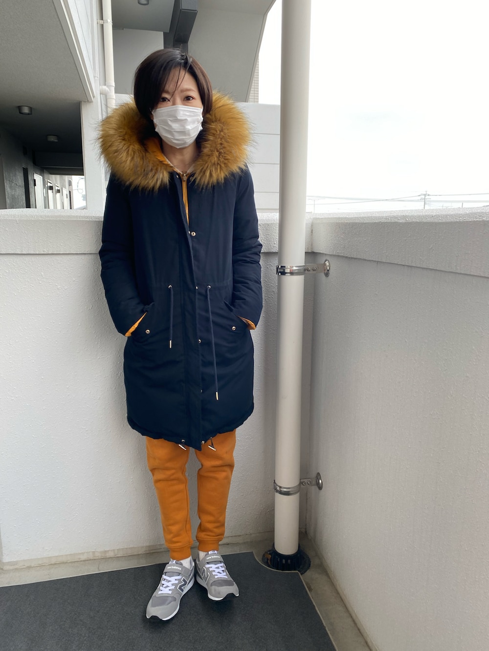 オレンジ系のスウェットパンツ、グレー系のスニーカー、ブラック系のダウンジャケット/コートを着用したレディースの冬コーディネートの2枚目の写真