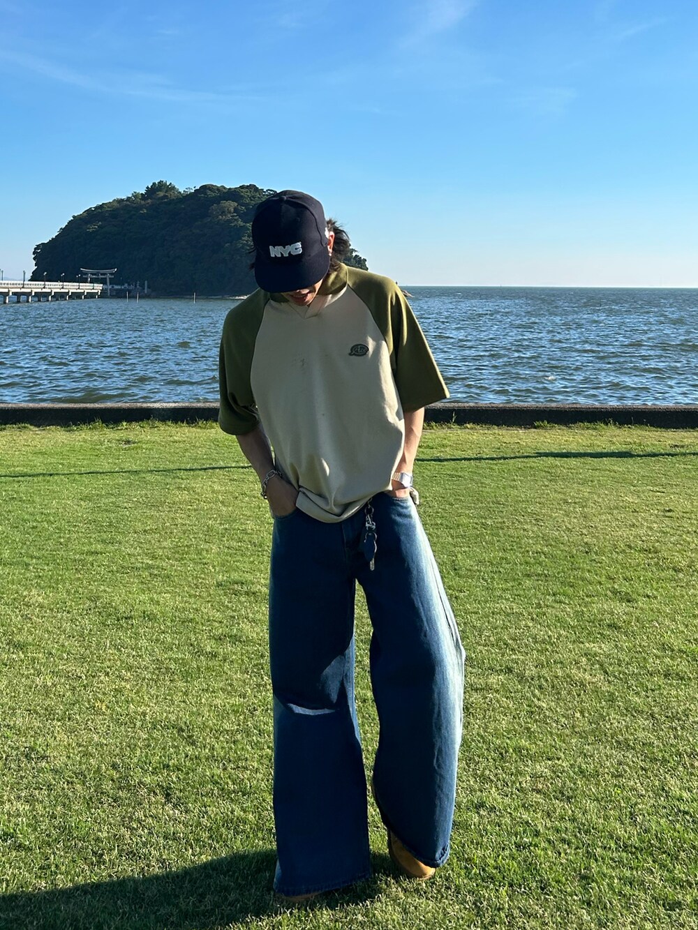 ベージュ系のトップス、ブルー系のデニムパンツ、ベージュ系のブーツを着用したメンズの夏コーディネートの2枚目の写真