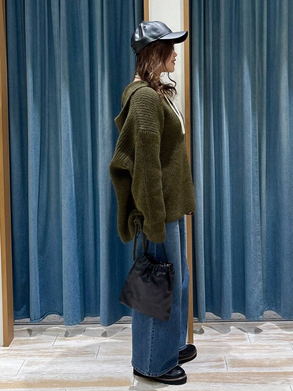 ブラック系のローファー、ブルー系のデニムパンツ、ブラック系のハンドバッグを着用したレディースの秋コーディネートの2枚目の写真