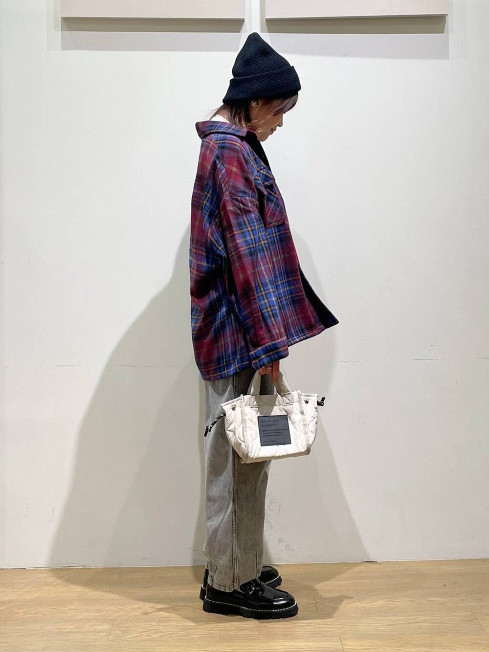 ホワイト系のショルダーバッグ、ブラック系のデニムパンツ、ブラック系のローファーを着用したレディースの秋コーディネートの3枚目の写真