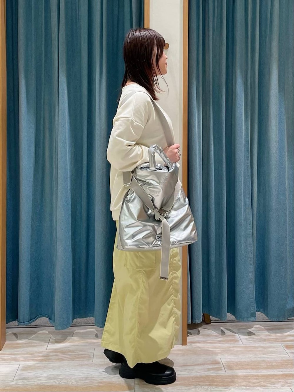 ブラック系のブーツ、ホワイト系のスウェット、シルバー系のトートバッグを着用したレディースの冬コーディネートの2枚目の写真