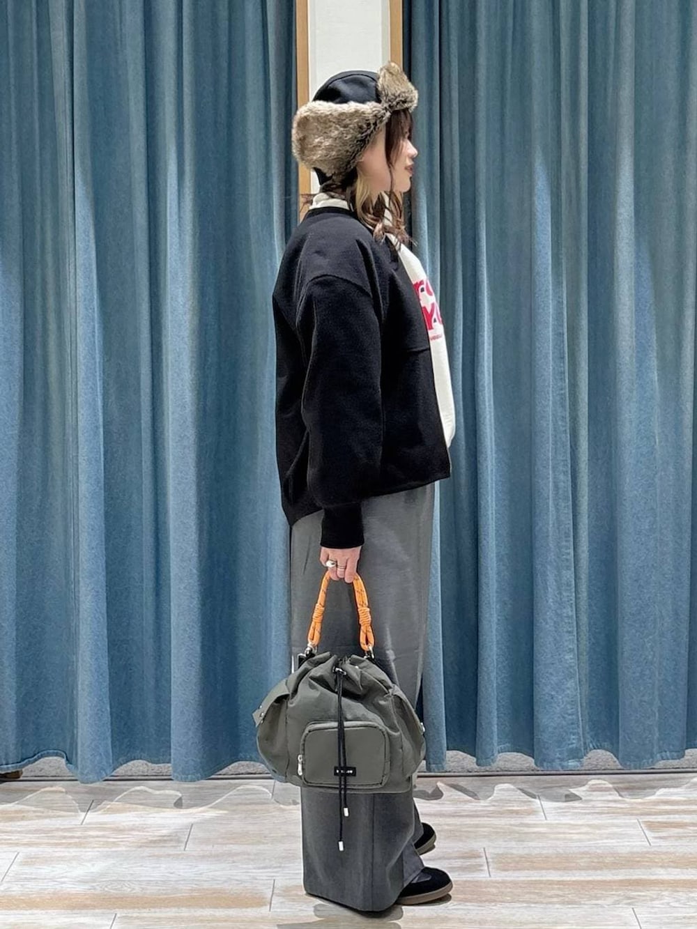 グレー系のその他パンツ、ブラック系のスニーカー、グリーン系のハンドバッグを着用したレディースの冬コーディネートの2枚目の写真