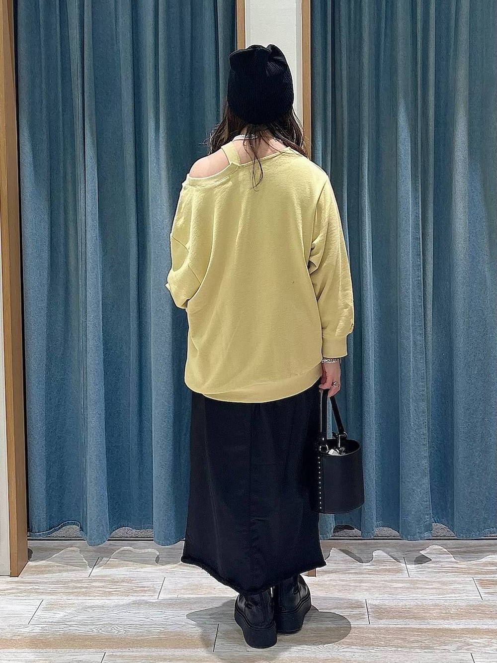 ブラック系のブーツ、イエロー系のスウェット、ブラック系のスカートを着用したレディースの冬コーディネートの3枚目の写真