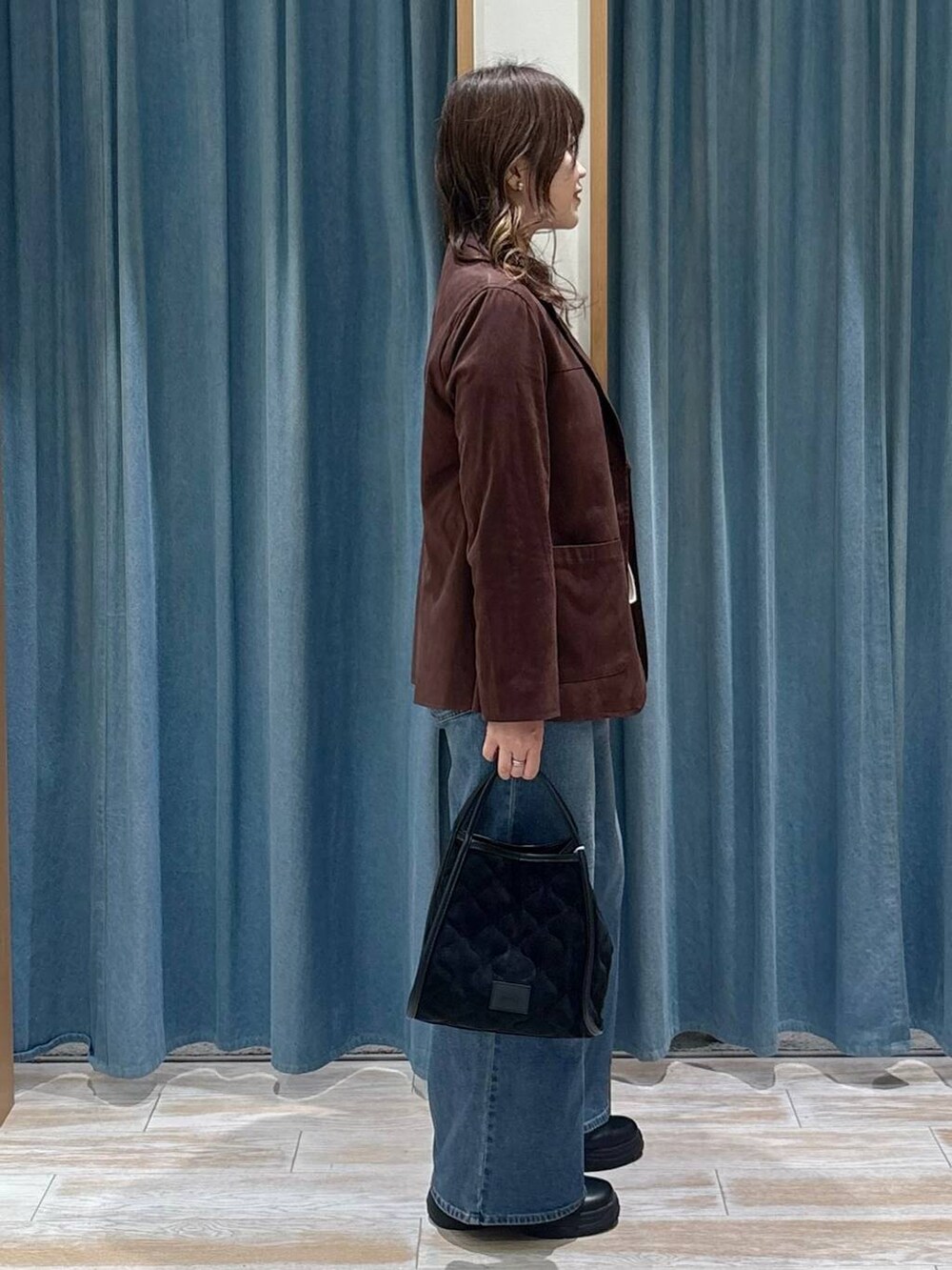 ブラック系のブーツ、ブラウン系のテーラードジャケット、ブルー系のデニムパンツを着用したレディースの秋コーディネートの2枚目の写真