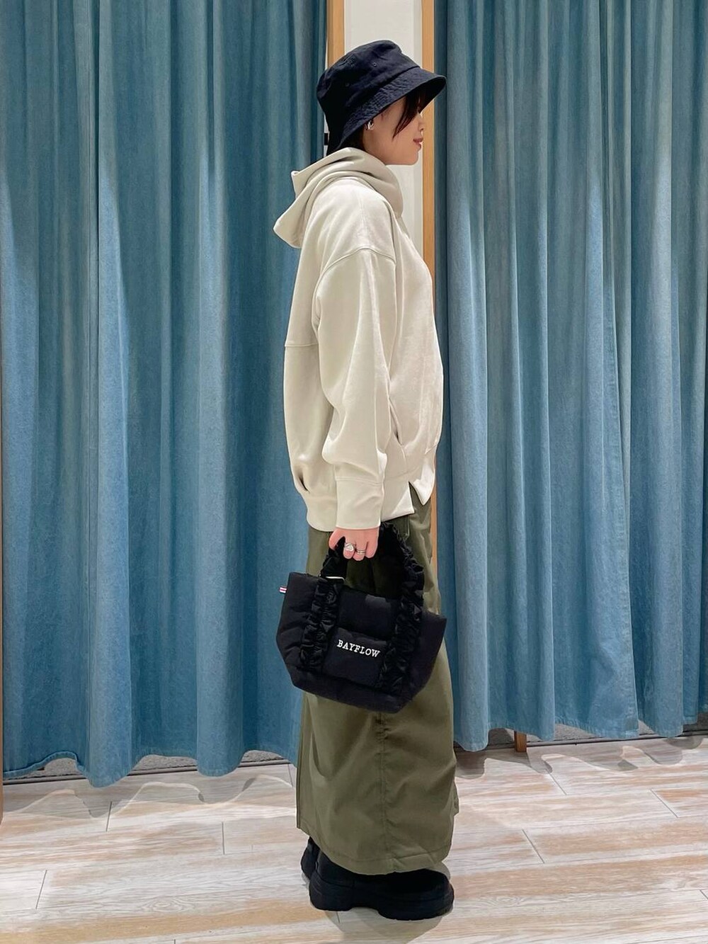 ホワイト系のパーカー、グリーン系のスカート、ブラック系のブーツを着用したレディースの秋コーディネートの2枚目の写真