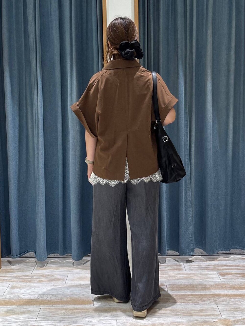 ブラック系のデニムパンツ、ブラック系のトートバッグ、ゴールド系のサンダルを着用したレディースの夏コーディネートの3枚目の写真
