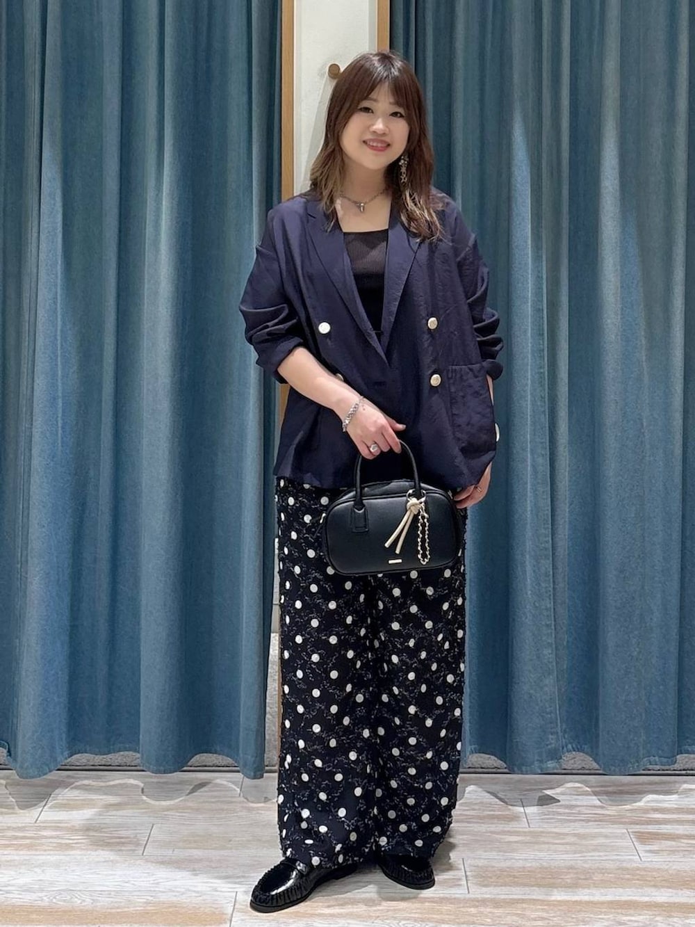 ブラック系のタンクトップ、ブラック系のローファー、ブラック系のハンドバッグを着用したレディースの春コーディネートの4枚目の写真