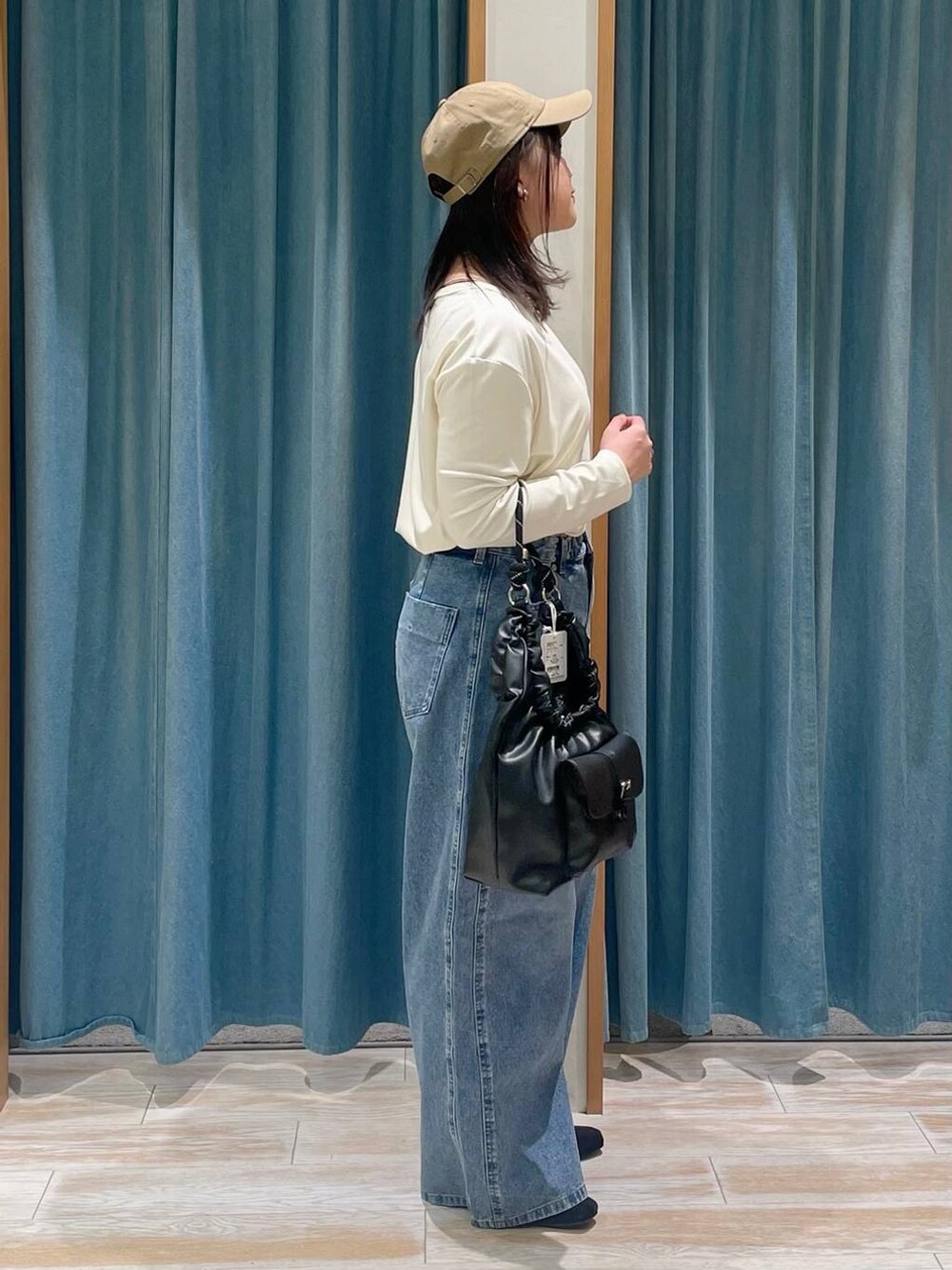 ブルー系のデニムパンツ、ホワイト系のTシャツ/カットソー、ブラック系のハンドバッグを着用したレディースの冬コーディネートの2枚目の写真