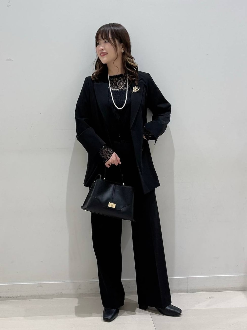 ブラック系のローファー、ブラック系のTシャツ/カットソー、ブラック系のスラックスを着用したレディースの冬コーディネートの4枚目の写真