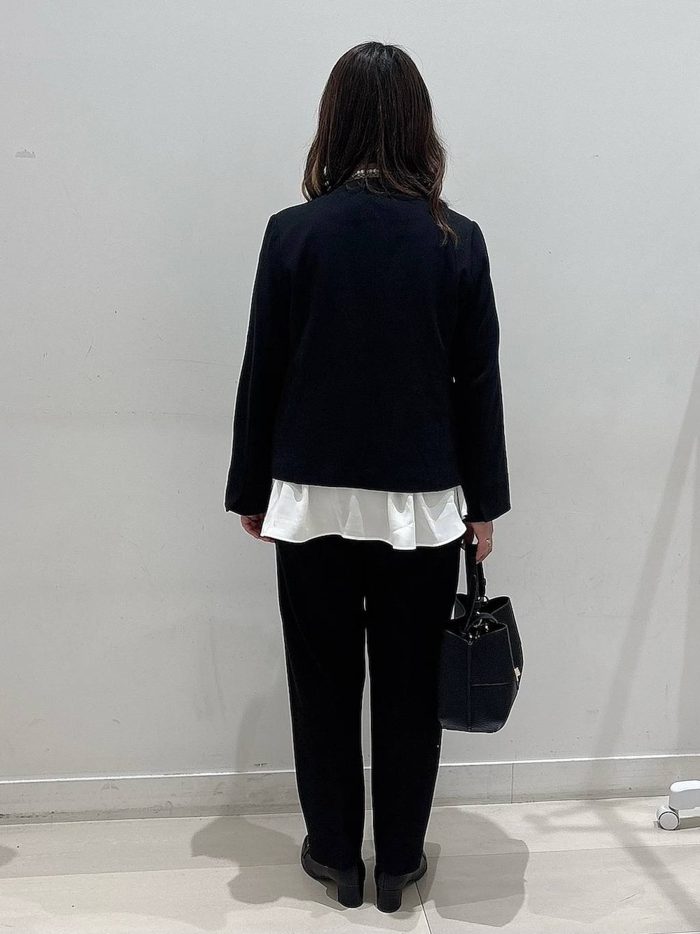 ブラック系のセットアップ、ブラック系のショルダーバッグ、ブラック系のローファーを着用したレディースの冬コーディネートの3枚目の写真