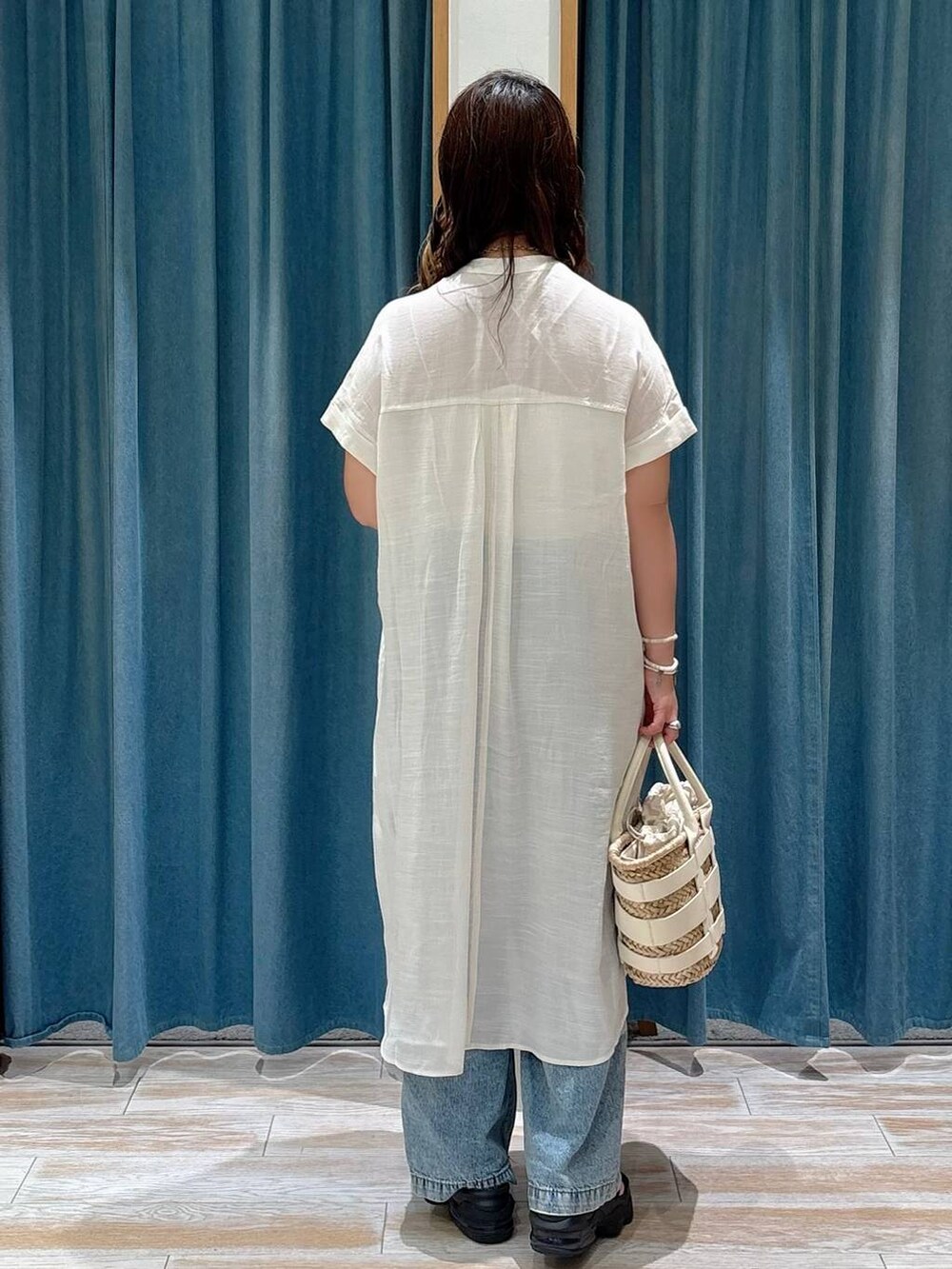 ホワイト系のキャミソール、ホワイト系のかごバッグ、ブルー系のデニムパンツを着用したレディースの夏コーディネートの3枚目の写真