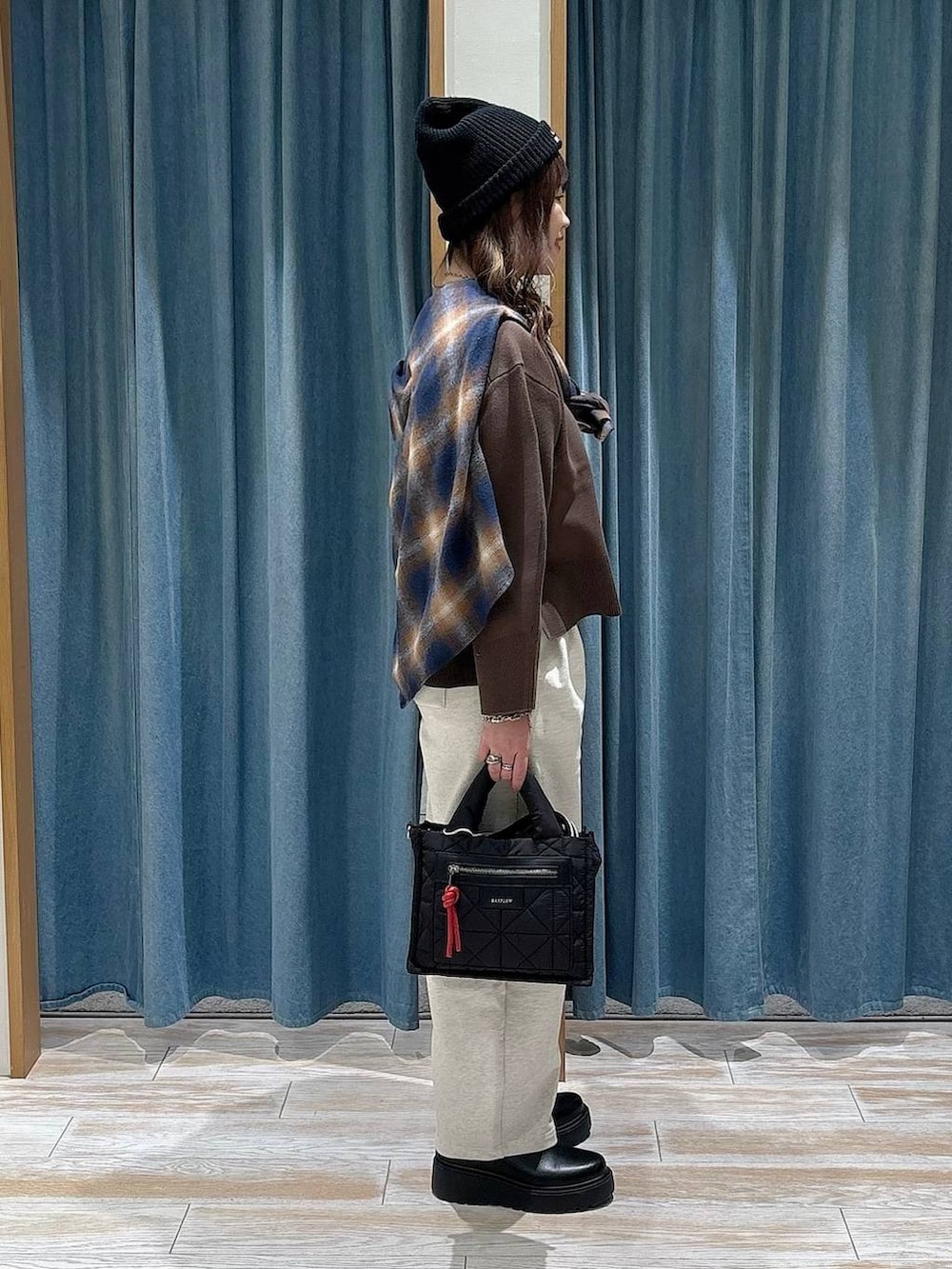 ブラック系のショルダーバッグ、ブラック系のブーツ、ブラウン系のニット/セーターを着用したレディースの冬コーディネートの2枚目の写真