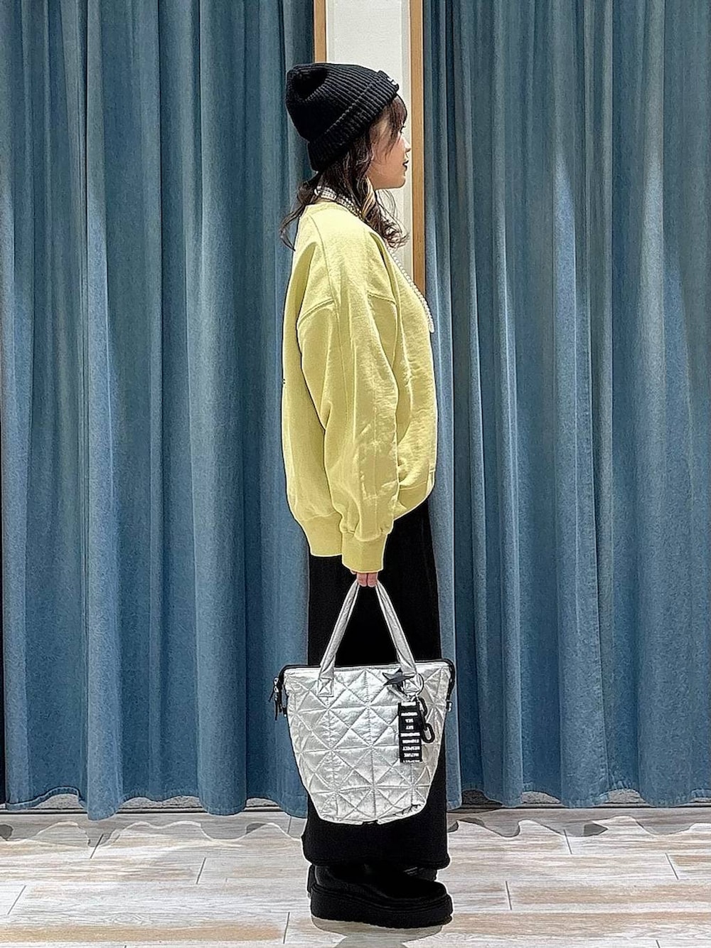 ブラック系のブーツ、イエロー系のスウェット、ブラック系のスカートを着用したレディースの冬コーディネートの2枚目の写真