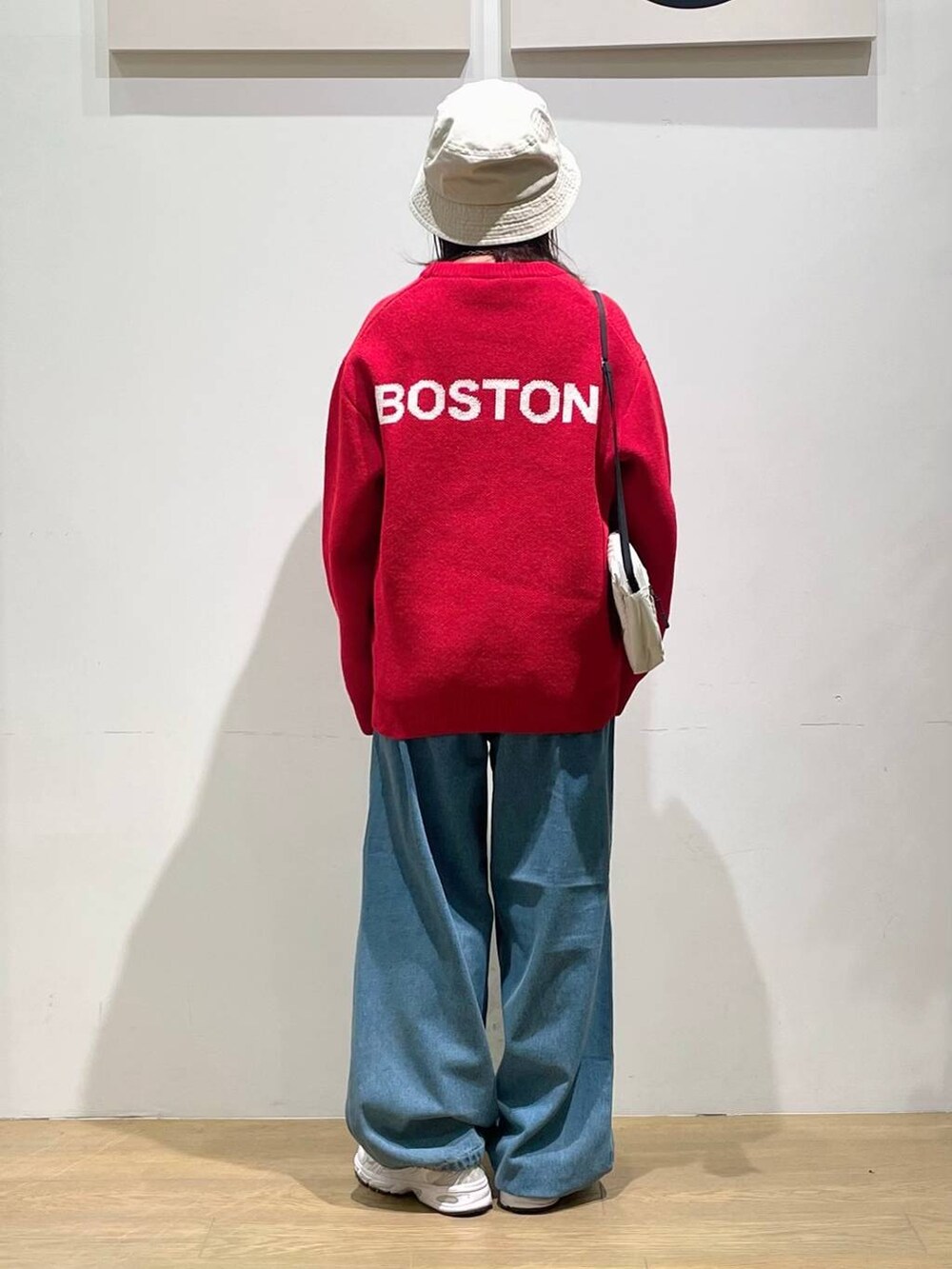 レッド系のニット/セーター、ブルー系のその他パンツ、ベージュ系のショルダーバッグを着用したレディースの秋コーディネートの3枚目の写真