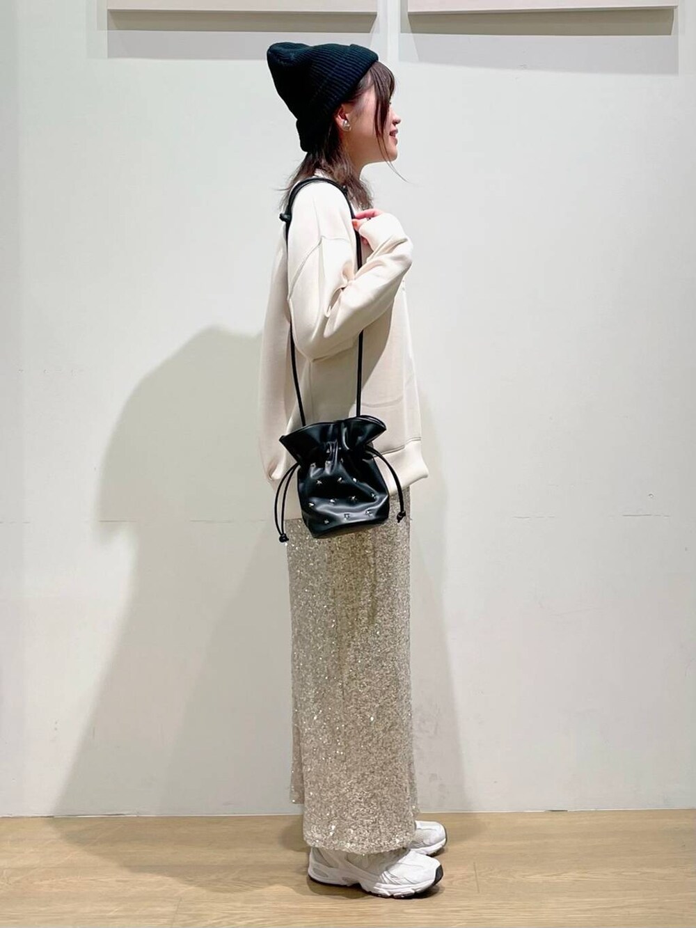 ブラック系のショルダーバッグ、ベージュ系のスカート、ホワイト系のTシャツ/カットソーを着用したレディースの秋コーディネートの2枚目の写真