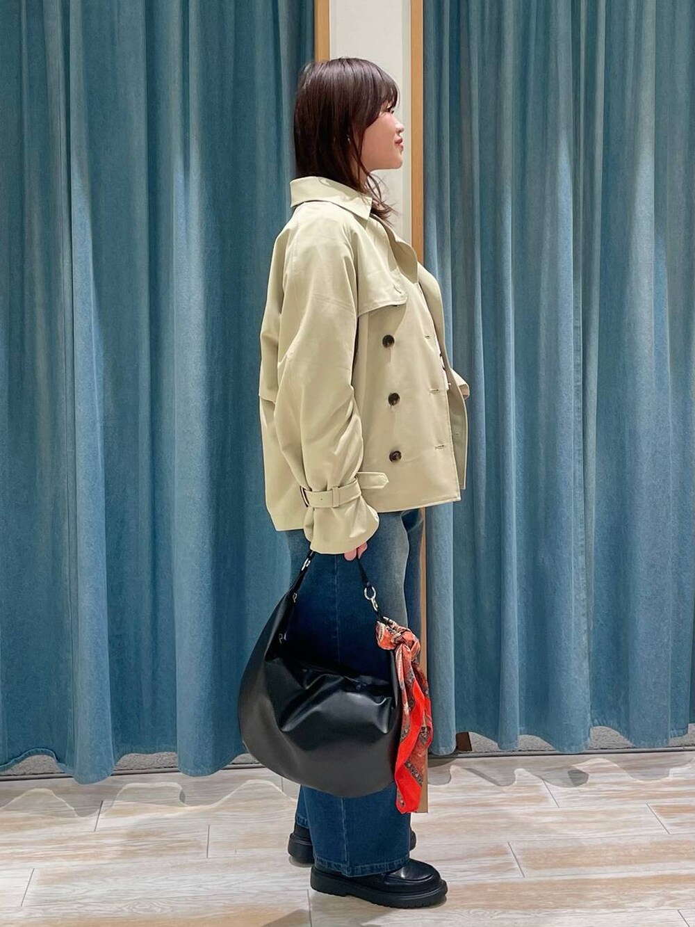 ベージュ系のトレンチコート、ブルー系のデニムパンツ、ホワイト系のTシャツ/カットソーを着用したレディースの冬コーディネートの2枚目の写真