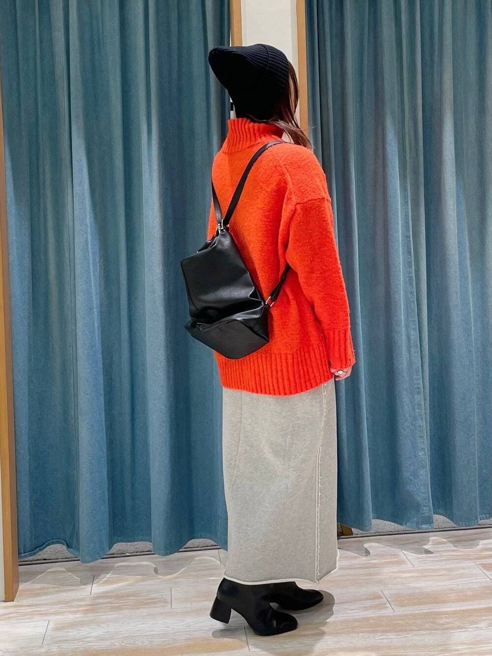 ブラック系のブーツ、ブラック系のショルダーバッグ、オレンジ系のニット/セーターを着用したレディースの冬コーディネートの2枚目の写真