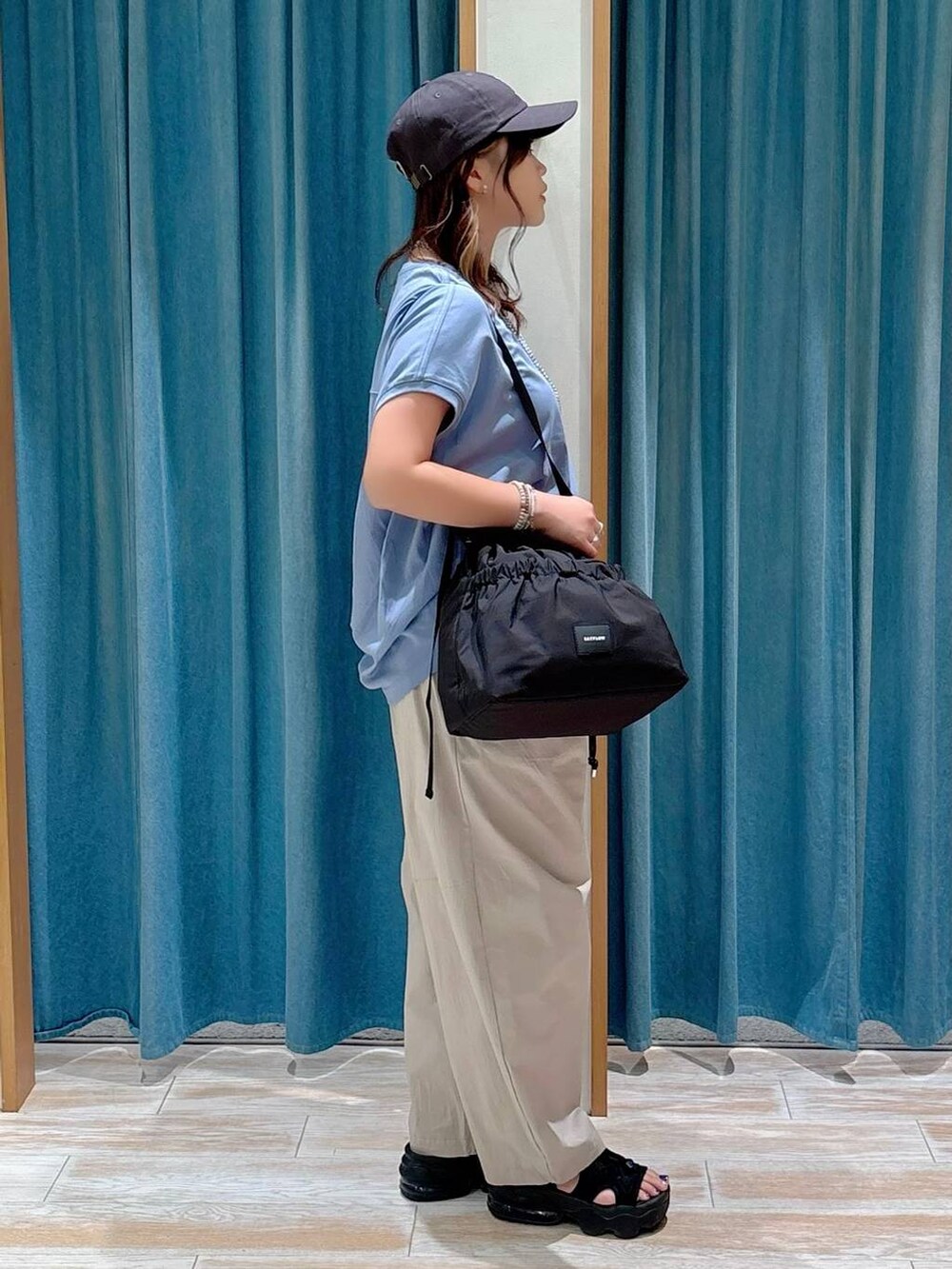 ブラック系のトートバッグ、ブルー系のTシャツ/カットソー、ベージュ系のその他パンツを着用したレディースの夏コーディネートの2枚目の写真