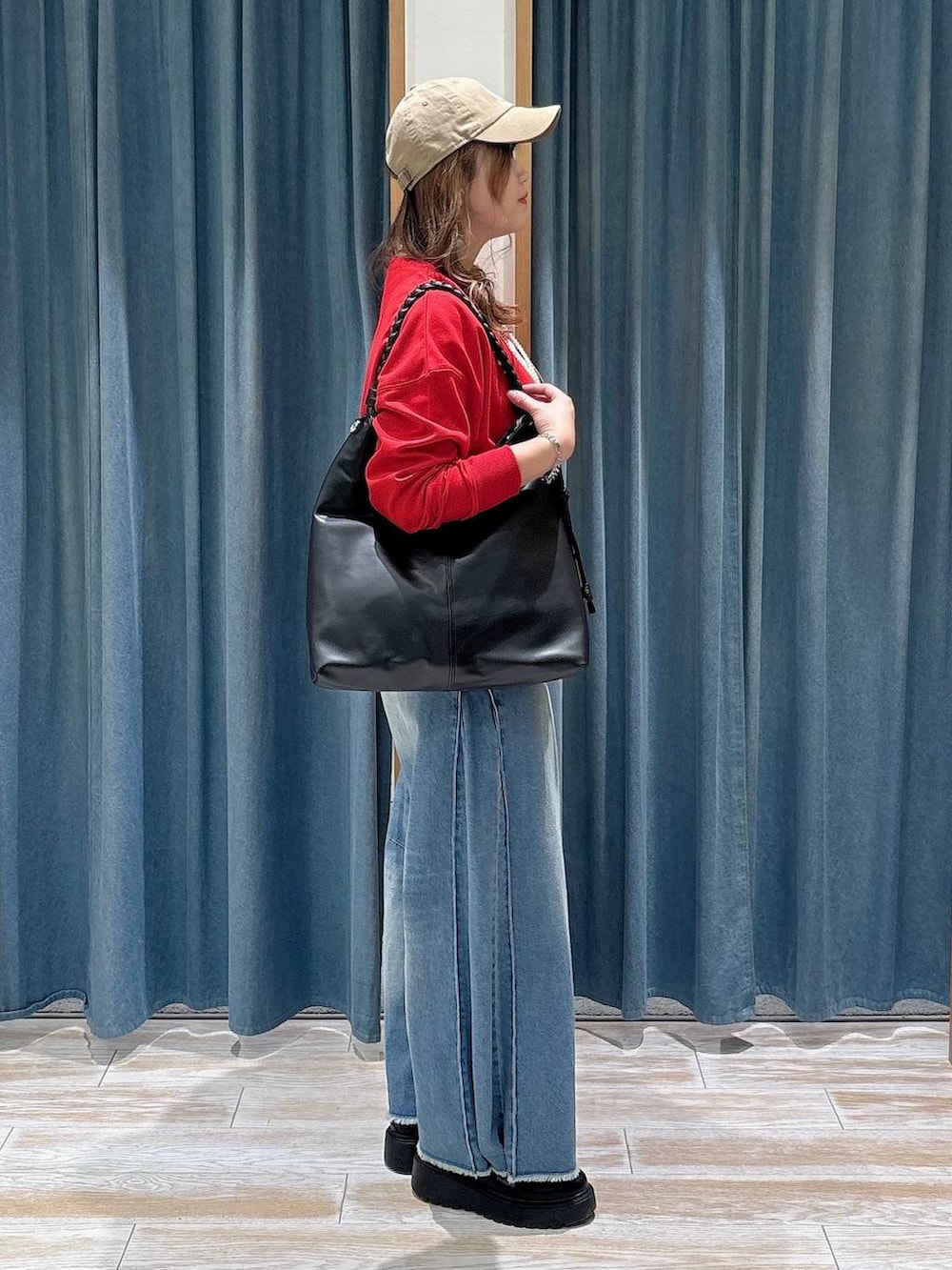 ブルー系のデニムパンツ、レッド系のカーディガン/ボレロ、ブラック系のブーツを着用したレディースの秋コーディネートの2枚目の写真