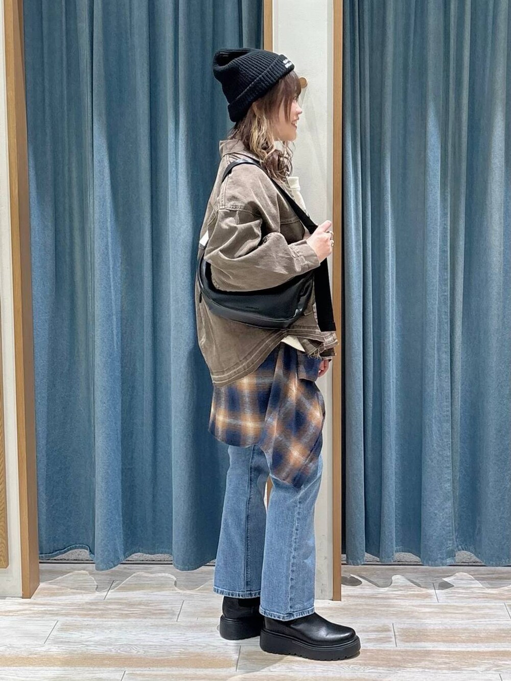 ブラック系のブーツ、ブルー系のデニムパンツ、ベージュ系のスウェットを着用したレディースの冬コーディネートの2枚目の写真