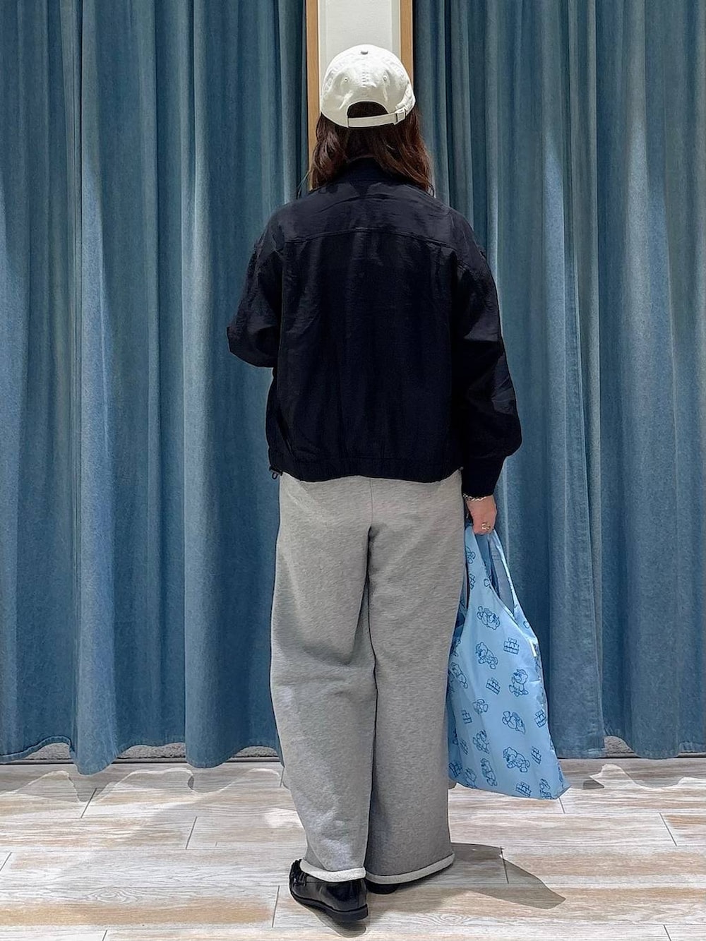 ブラック系のローファー、ブルー系のエコバッグ/サブバッグ、ブラック系のブルゾンを着用したレディースの春コーディネートの3枚目の写真