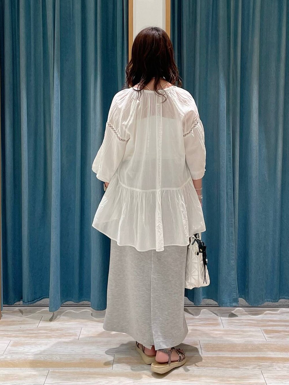 ホワイト系のハンドバッグ、ホワイト系のシャツ/ブラウス、グレー系のスカートを着用したレディースの春コーディネートの3枚目の写真