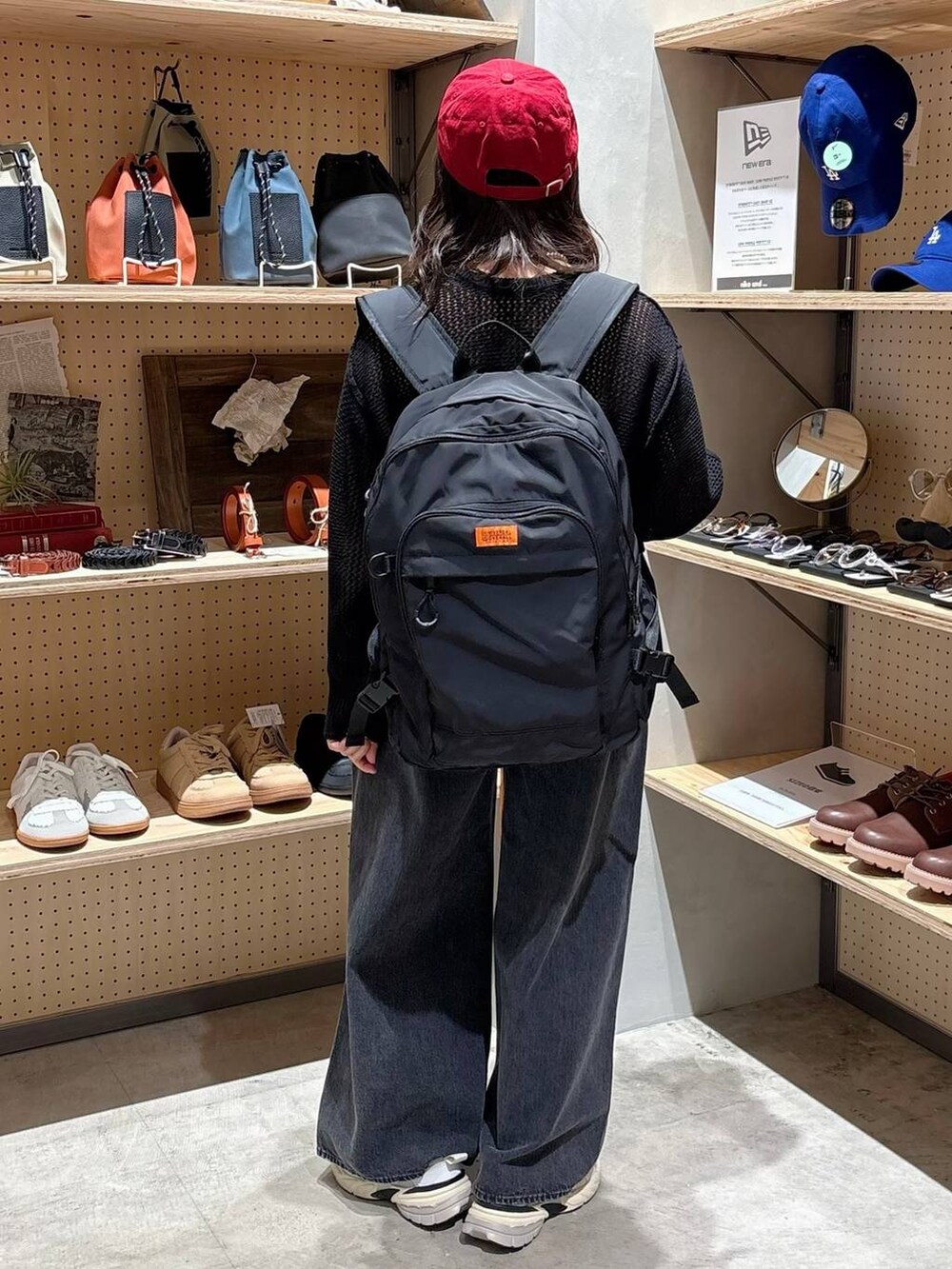 グレー系のデニムパンツ、ブラック系のバックパック/リュック、ブラック系のTシャツ/カットソーを着用したレディースの秋コーディネートの3枚目の写真