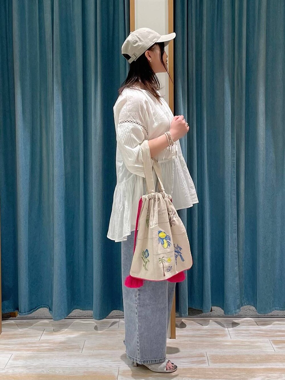 ホワイト系のキャミソール、ブルー系のデニムパンツ、シルバー系のサンダルを着用したレディースの春コーディネートの2枚目の写真