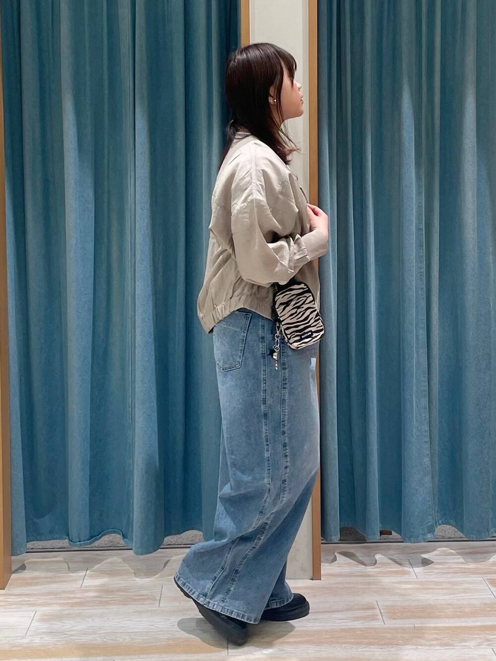 ベージュ系のショルダーバッグ、ブルー系のデニムパンツ、ホワイト系のTシャツ/カットソーを着用したレディースの春コーディネートの2枚目の写真