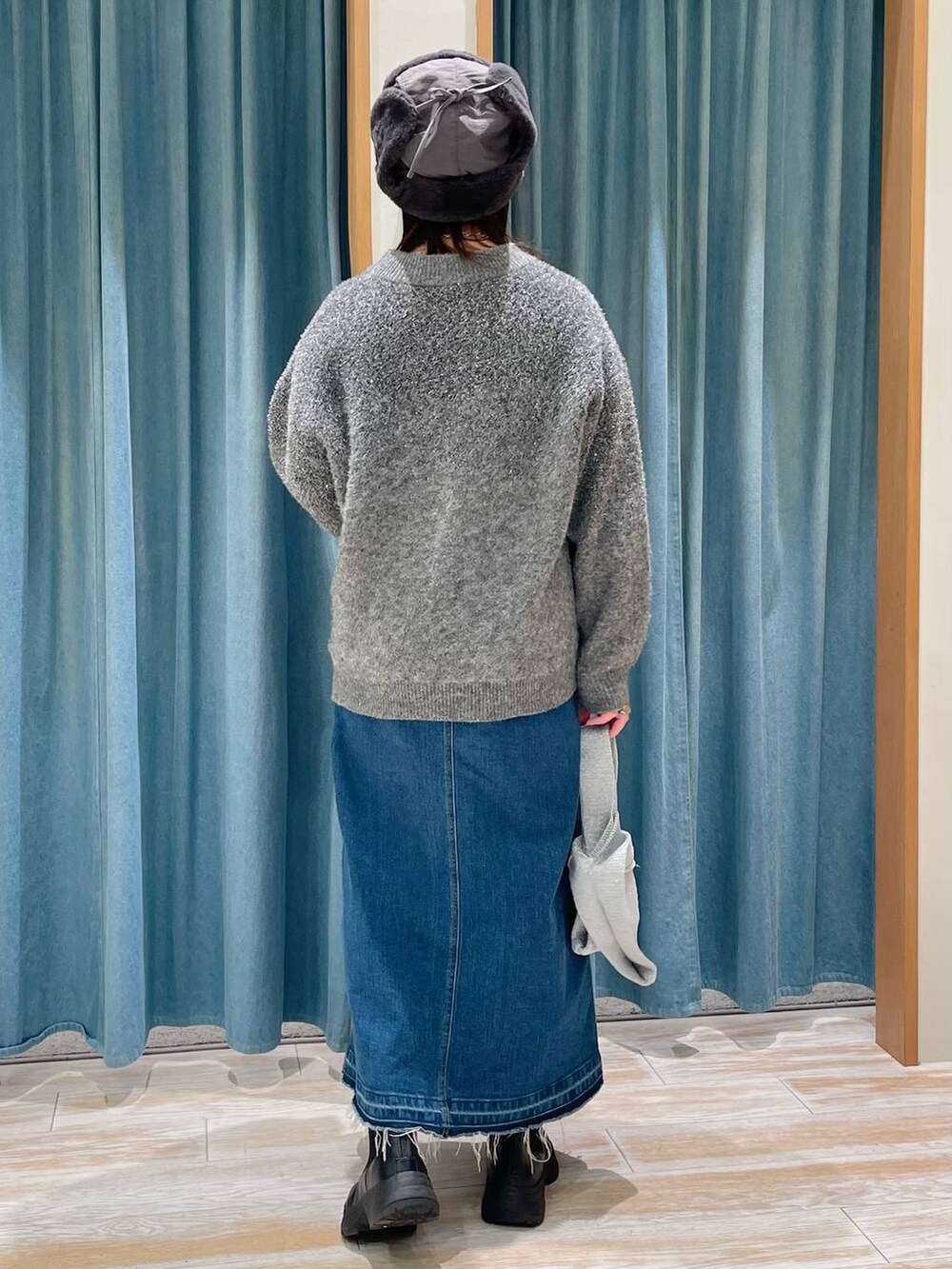 ブルー系のデニムスカート、ブラック系のブーツ、グレー系のハンドバッグを着用したレディースの冬コーディネートの3枚目の写真