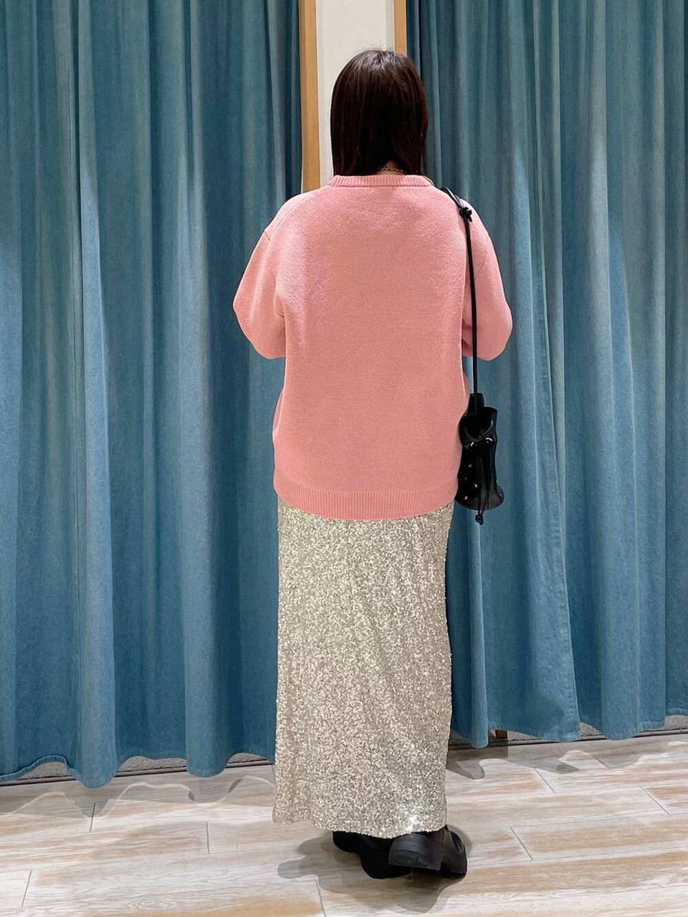 ピンク系のニット/セーター、ブラック系のショルダーバッグ、ブラック系のブーツを着用したレディースの冬コーディネートの2枚目の写真